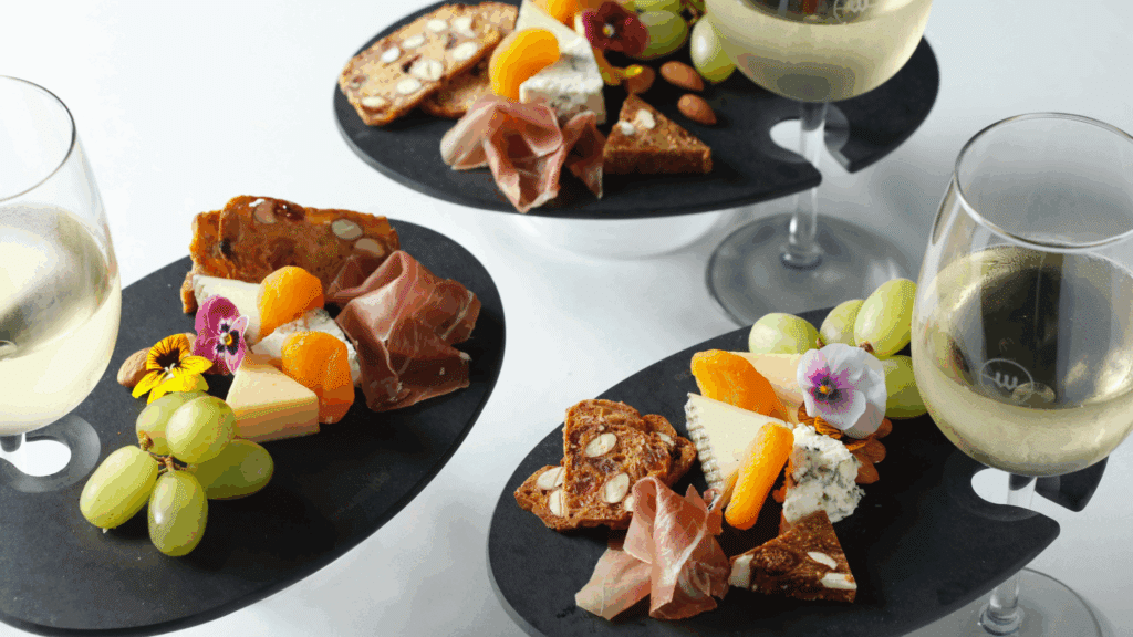 Three mini charcuterie boards with wine glasses in them