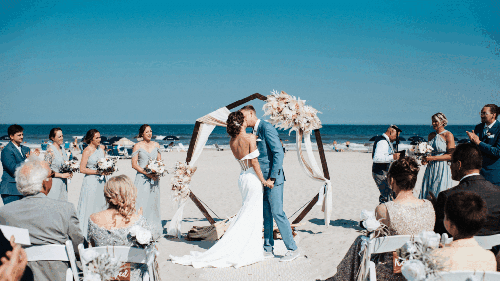 Beach wedding ceremony with an octagon-shaped arch and flowers as the decor