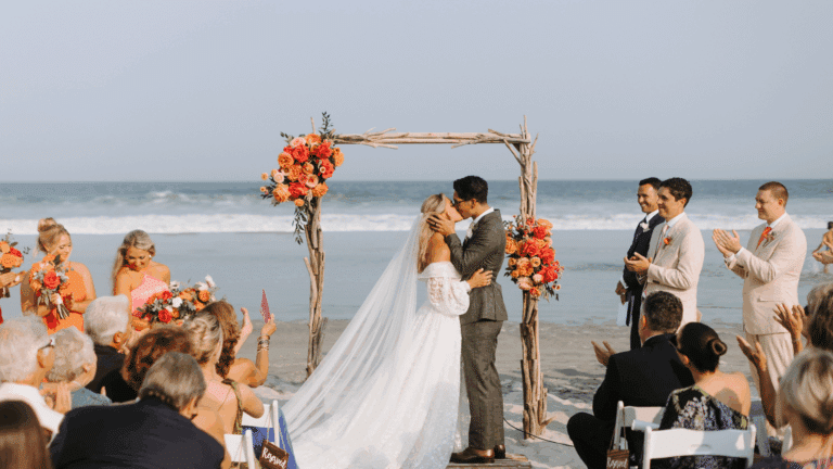 Bride and groom kissing at a beach wedding ceremony