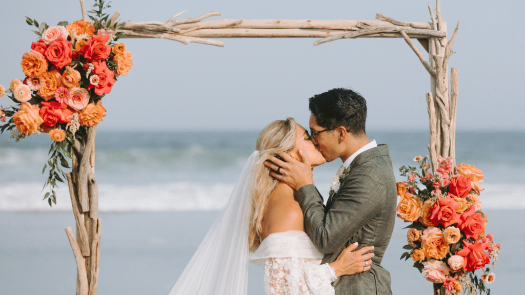 Bride and groom kissing in front of a drift wood arch