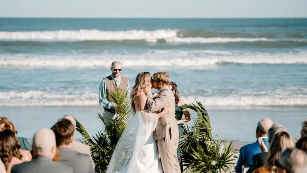 Bride and groom kissing at a beach wedding ceremony