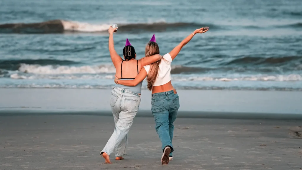 Friends hugging and skipping on the beach at a bachelorette party