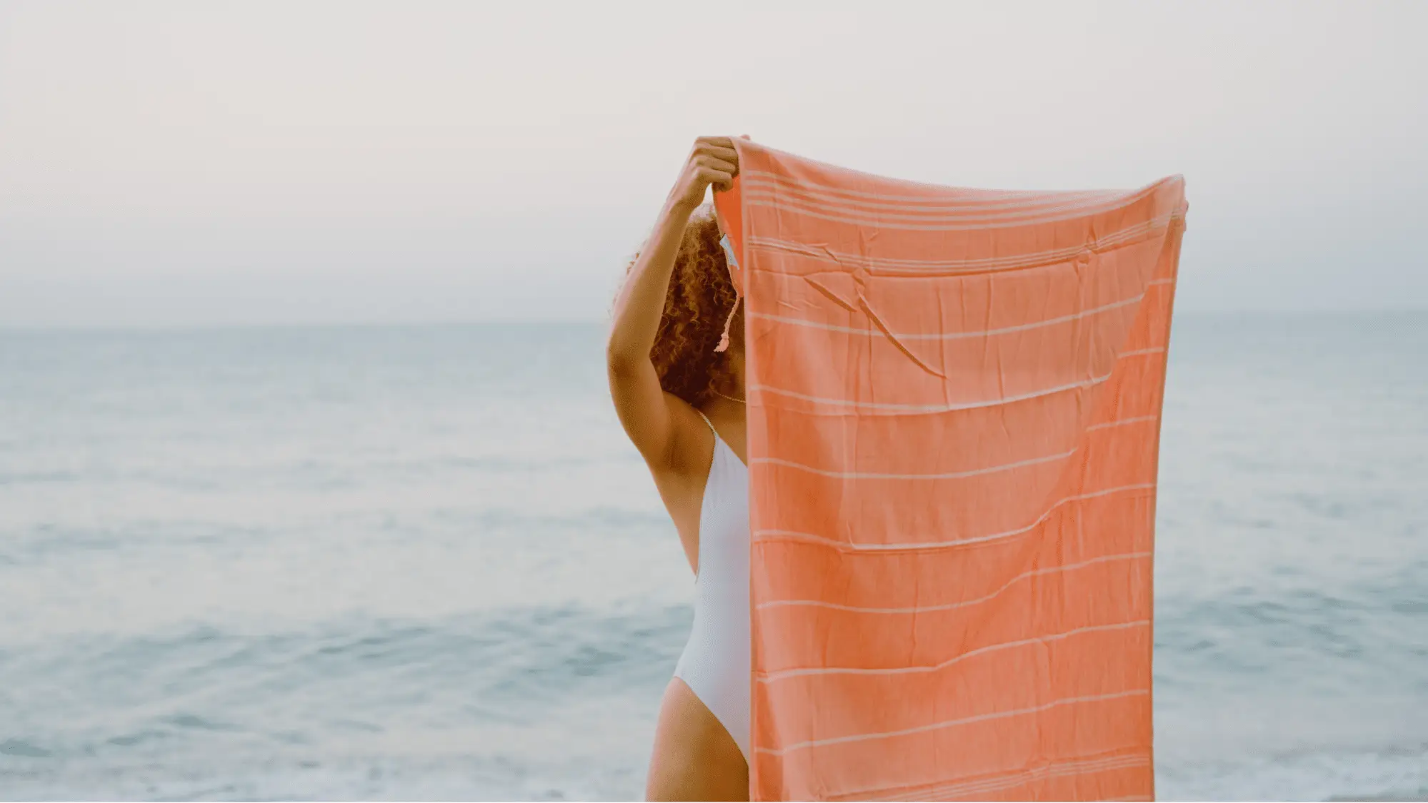 Woman holding a beach towel by the ocean