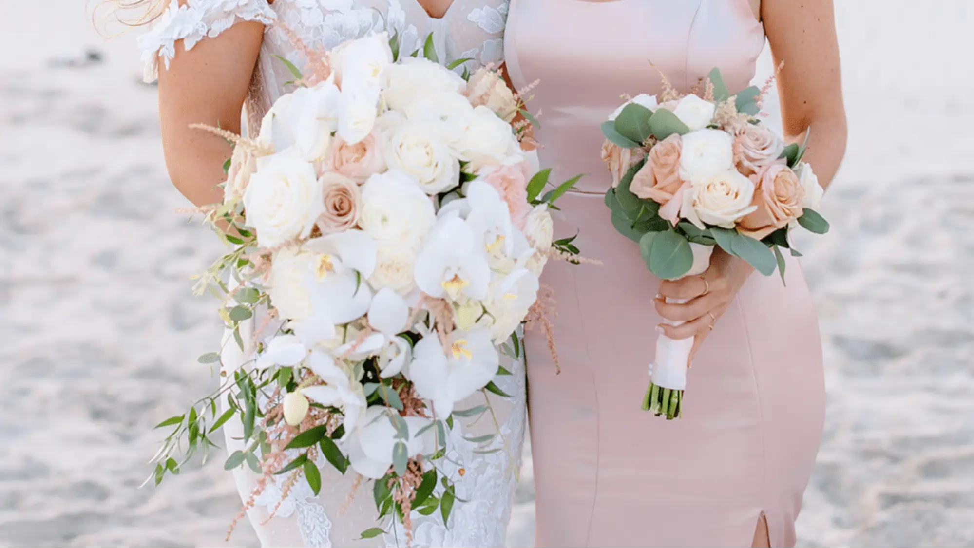Bride and her bridesmaid holding bouquets with white and light pink roses accented with bits of greenery