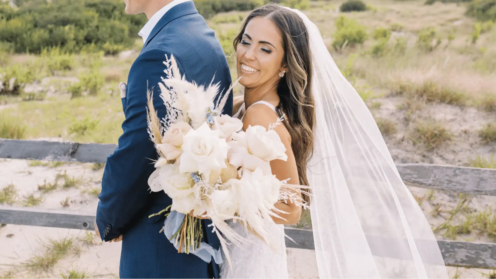 Bride holding a bouquet of pink and white roses with pampas grass